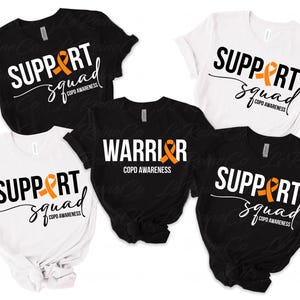 Puede incluir: Cinco camisetas con diferentes diseños relacionados con la concienciación sobre la EPOC. Dos camisetas negras presentan el texto "SUPPORT squad COPD AWARENESS" con una cinta naranja. Una camiseta negra presenta el texto "WARRIOR COPD AWARENESS" con una cinta naranja. Dos camisetas blancas presentan el texto "SUPPORT squad COPD AWARENESS" con una cinta naranja.