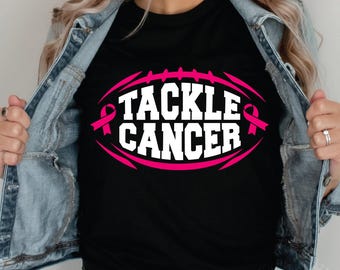 May include: Black t-shirt with a pink football graphic and the text "Tackle Cancer" with pink ribbon accents.