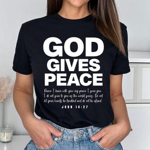 May include: Black t-shirt with white text that reads "GOD GIVES PEACE" and a Bible verse from John 14:27.