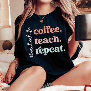 May include: Black t-shirt with the text "#teacherlife coffee. teach. repeat." in colorful lettering.