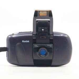 Op de afbeelding: Een zwarte Kodak 35mm camera met een ingebouwde flitser en een Ektanar lens.