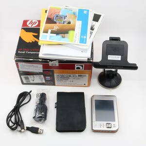 May include: A silver HP iPAQ nc5700 Travel Companion PDA with a black case, car charger, USB cable, and a black car mount. The box for the PDA is also visible in the image.