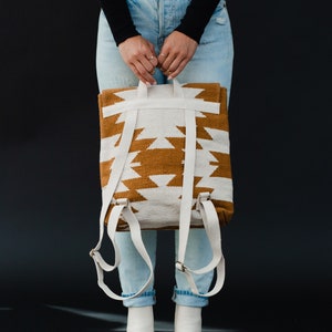 May include: A white and brown woven backpack with adjustable straps. The backpack has a geometric pattern.