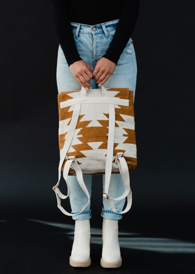 May include: A white and brown woven backpack with adjustable straps. The backpack has a geometric pattern.