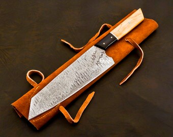 May include: A Damascus steel chef's knife with a wooden handle and a leather sheath. The knife has a unique pattern on the blade.