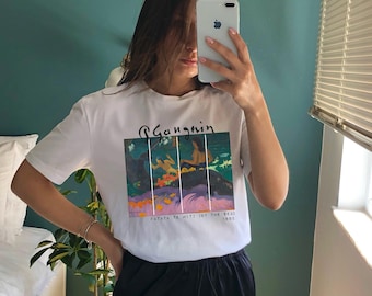 May include: White t-shirt with a graphic print of a painting by artist "Gagnin" titled "Fatata Te Hiti (By The Sea)" 1892.