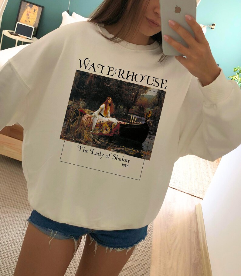 May include: White sweatshirt with a graphic print of a painting by John William Waterhouse titled "The Lady of Shalott" from 1888. The painting depicts a woman in a boat on a river.