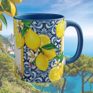 May include: A blue and white ceramic mug with a lemon design. The mug has a blue handle and a white interior. The lemon design features lemons, leaves, and flowers.
