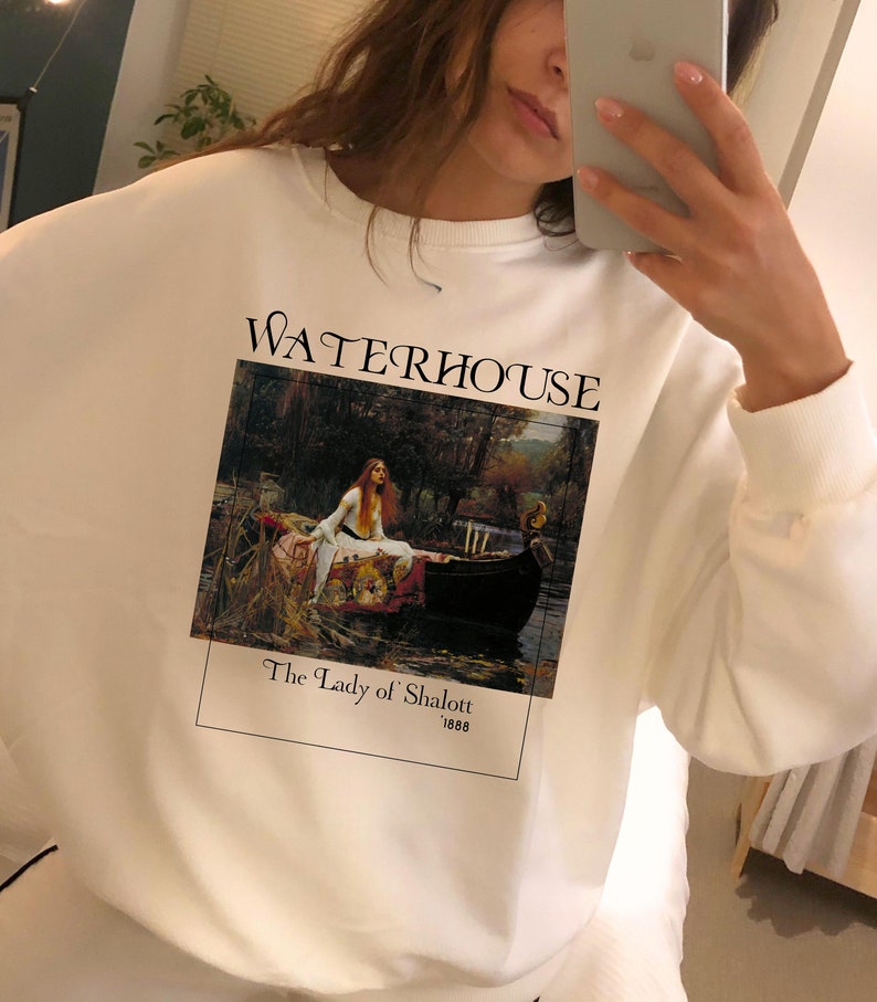 May include: White sweatshirt with a graphic print of a painting by John William Waterhouse titled "The Lady of Shalott" from 1888. The text "WATERHOUSE" is printed above the painting.