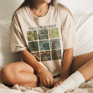 May include: A beige t-shirt with a graphic print of nine squares featuring different floral patterns. The text "WILLIAM MORRIS" is printed above the squares.