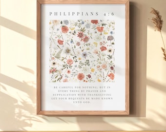 May include: A framed wall art print featuring a central square pattern of watercolor-style wildflowers in shades of red, pink, yellow, and blue. The text reads Philippians 4:6 and includes the full verse about prayer and supplication in black.