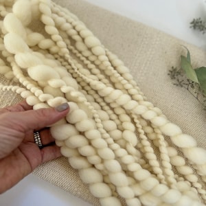 以下が含まれることがあります： ベージュの布地に、ふわふわとした質感の白い糸が並んでいます。