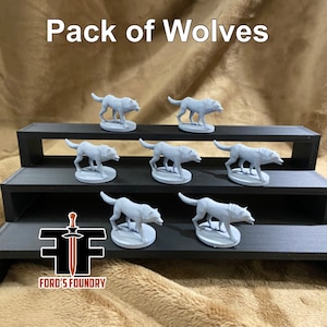 May include: A pack of seven gray wolf figurines displayed on a black tiered stand. The text "Pack of Wolves" is at the top of the image. The Ford's Foundry logo is at the bottom.