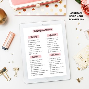 May include: A pink and white checklist on a tablet screen with the title "Daily Self-Care Checklist". The checklist is divided into three sections: Morning, Afternoon, and Evening. Each section has a list of self-care activities, such as meditation, drinking water, eating a healthy breakfast, and getting enough sleep.