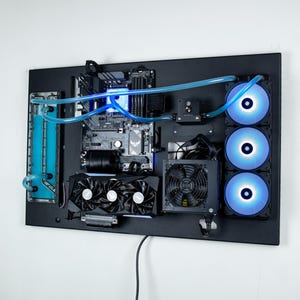 May include: A black computer case with a custom water-cooling system. The case is mounted on a wall and features a clear reservoir, blue tubing, and three blue LED fans.