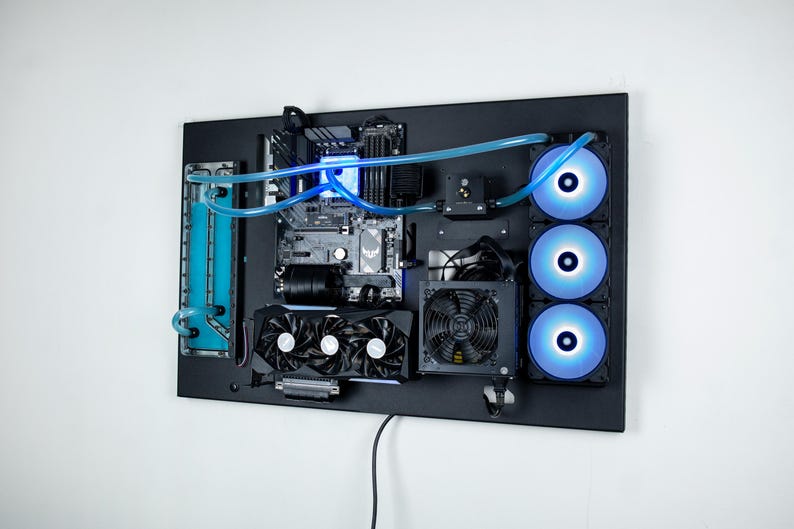 May include: A black computer case with a custom water-cooling system. The case is mounted on a wall and features a clear reservoir, blue tubing, and three blue LED fans.