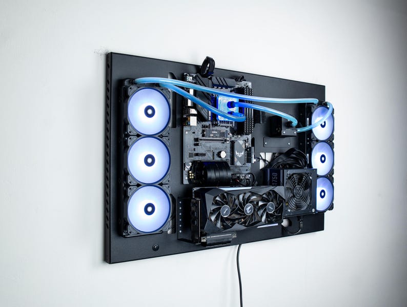 May include: A black computer case with a motherboard, graphics card, and multiple fans. The case is mounted on a wall and has blue tubing running through it.