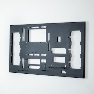 May include: A black metal frame with cutouts for various components. The frame is designed for a computer case and has slots for motherboard, hard drives, and other components.