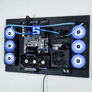 May include: A black computer case with a custom water cooling system. The case has a motherboard, graphics card, and power supply installed. The water cooling system includes a reservoir, pump, and radiator. The case is mounted on a wall.