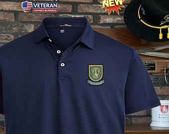 Può includere: Una polo blu navy con una toppa ricamata gialla e blu sul petto sinistro. La toppa presenta uno scudo con un cavaliere e un cavallo, e il testo "1st  CAVALRY".