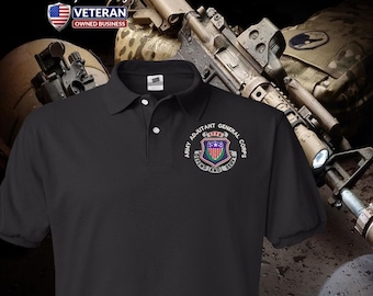 Può includere: Polo nero con l'emblema dell'Army Adjutant General Corps ricamato sul petto sinistro. L'emblema presenta uno scudo con elementi rossi, bianchi e blu. La maglietta presenta anche il testo "OP Alpha Designs" e "Veteran Owned Business".