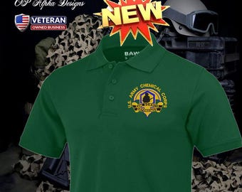 Può includere: Polo verde scuro con l'emblema del U.S. Army Chemical Corps. La maglietta ha una chiusura a bottoni e maniche corte. L'immagine include anche una grafica "NUOVO" e il testo "OP Alpha Designs" e "Veteran Owned Business".