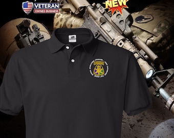 Può includere: Polo nero con una toppa ricamata bianca che presenta l'emblema della 101a Divisione aviotrasportata. La toppa include le parole "Operations Command Joint Capabilities", "Airborne" e "(SOC-JC)".