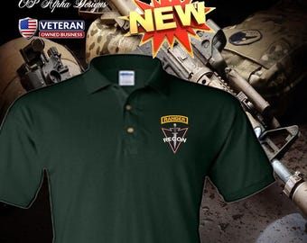 Può includere: Polo di colore verde scuro con un piccolo stemma "RANGER RECON". La camicia ha una paramontura a tre bottoni e maniche corte. L'immagine include anche una grafica "NEW" e un logo "VETERAN OWNED BUSINESS".