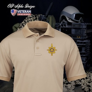 May include: A tan polo shirt with a gold embroidered patch featuring a star with a sword and blue accents. The patch is on the left side of the shirt. The shirt has a button-down collar and short sleeves.