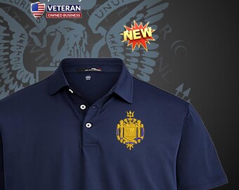 Può includere: Polo blu navy con un'emblema oro e blu sul petto. La camicia ha una chiusura a tre bottoni e un colletto. L'immagine include anche una grafica "NEW" e un logo "Veteran Owned Business".
