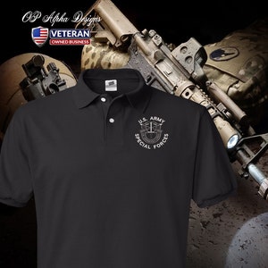 Pu&ograve; includere: Polo nero con un logo ricamato bianco delle Forze Speciali dell'esercito americano. Il logo presenta un'aquila alata con fucili incrociati e un rotolo con le parole "De Oppresso Liber" sotto.