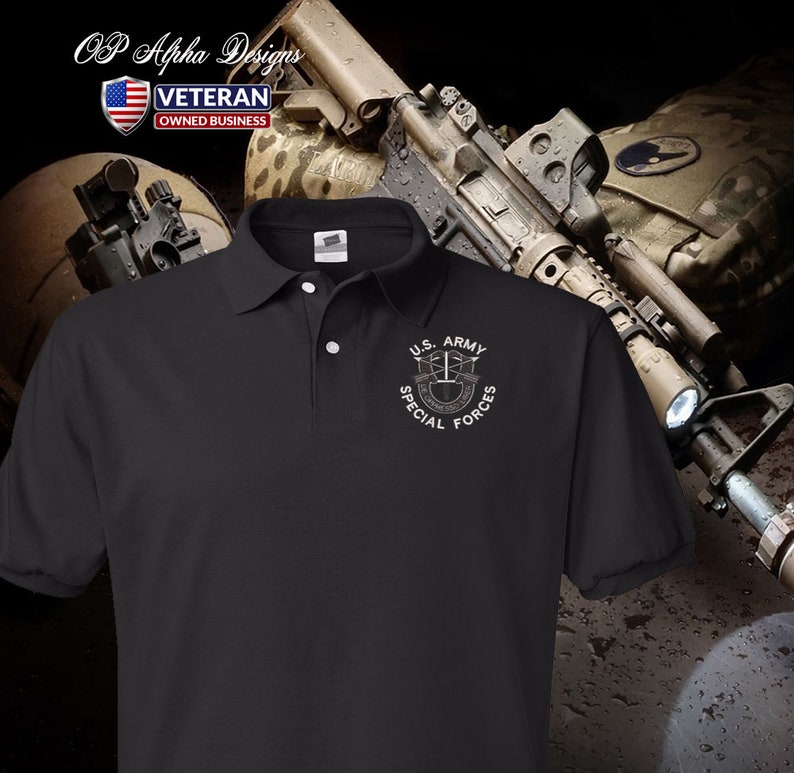 Pu&ograve; includere: Polo nero con un logo ricamato bianco delle Forze Speciali dell'esercito americano. Il logo presenta un'aquila alata con fucili incrociati e un rotolo con le parole "De Oppresso Liber" sotto.