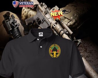 Può includere: Una polo nera con un piccolo stemma ricamato sul petto sinistro. Lo stemma presenta una forma di picche in nero, rosso e giallo con il testo latino FORTIOR SIMUL QUAM SEORSUM. La maglia è dotata di un colletto classico e due bottoni bianchi.