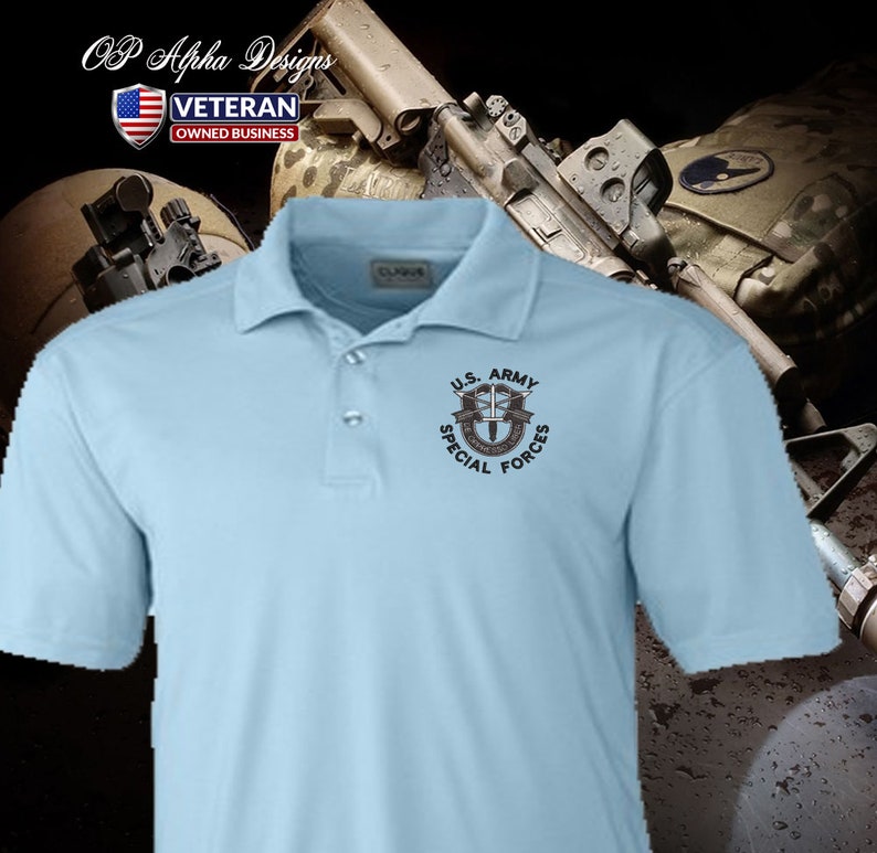 Pu&ograve; includere: Una polo blu chiaro con una toppa ricamata nera che dice "U.S. ARMY SPECIAL FORCES" e presenta un pugnale stilizzato e ali.