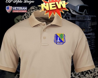 Può includere: Polo beige con abbottonatura a tre bottoni e un piccolo stemma sul petto. Lo stemma presenta un design blu, giallo e verde con testo. Il testo "NEW" è anche visibile.