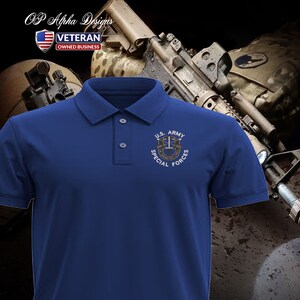 Pu&ograve; includere: Una polo blu reale con una toppa ricamata bianca che dice "U.S. ARMY SPECIAL FORCES" con un distintivo militare al centro.