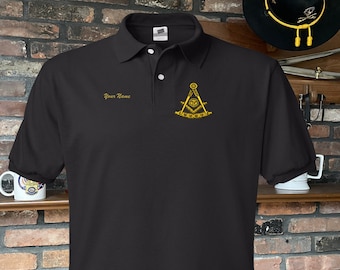 Può includere: Polo nero con un simbolo massonico ricamato in oro sul petto destro. La camicia ha un colletto abbottonato e maniche corte.