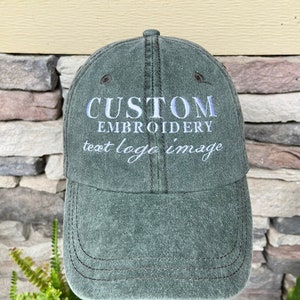 May include: A dark green baseball cap with the text "CUSTOM EMBROIDERY text logo image" embroidered in white on the front.