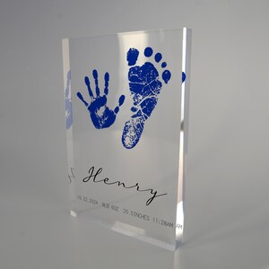 Op de afbeelding: Een heldere acrylblok met een blauwe handafdruk en voetafdruk, de naam "Henry" in cursief, en de datum "10.22.2024", het gewicht "8lb 5oz", de lengte "20.5 inch", en de tijd "11:28AM".