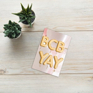 Op de afbeelding: Gouden folie letterballonnen die "BCB-YAY" spellen op een roze en witte achtergrond.