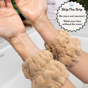 May include: Two tan wristbands are shown, designed to prevent water from running down the arms while washing the face. The text "Skip The Drip" and "No more wet counters! Wash your face without the mess!" is visible.