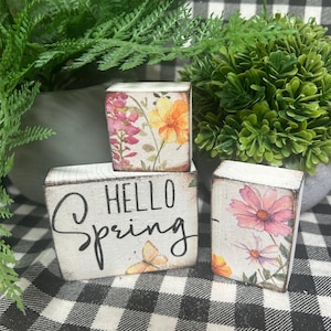 May include: A handmade wooden sign with the text "Welcome" in a handwritten style. The sign is painted white with a distressed finish and features a small, decorative heart. It is designed for indoor or outdoor use.