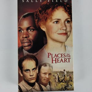 May include: A white ceramic mug with a black handle and the text "But First, Coffee" in a bold, black font. The mug is set against a neutral background, highlighting its simple design.