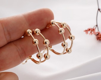May include: Gold hoop earrings with multiple rows of small, round beads.