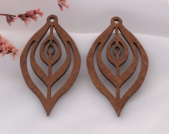 May include: A pair of wooden leaf-shaped earrings with a cut-out design. The earrings are a warm brown colour and have a small hole at the top for hanging. The design features concentric leaf shapes within the larger leaf outline.