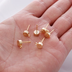 May include: Five gold-toned earring posts with a loop on the top. The posts are round and have a smooth finish.