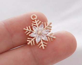 May include: Gold snowflake charm with clear crystal accents. The snowflake has a loop at the top for attaching to jewelry.