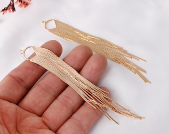 May include: A pair of long gold dangle earrings with a fringe design. The earrings are made of thin, linked chains that create a cascading effect.