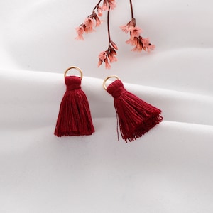 May include: Two red tassel ornaments with gold rings. The tassels are made of soft, fluffy yarn and are perfect for adding a touch of whimsy to any project.