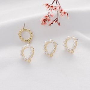 Puede incluir: Pendientes de metal dorado con un dise&ntilde;o circular. Cada pendiente presenta un anillo de peque&ntilde;as perlas blancas. Los pendientes tienen un cierre de poste y un peque&ntilde;o lazo en la parte inferior. Una ramita de flores rosas est&aacute; en el fondo.